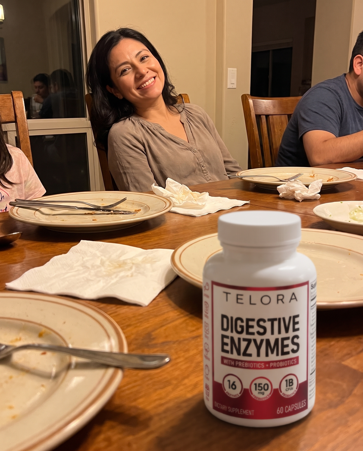 Mujer relajada en la mesa después de comer, con el bote de Enzimas Digestivas